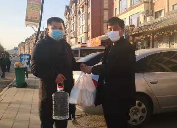 本次爱心捐赠发起人赵庆友（右）将口罩和酒精送到乡镇干部手中 摄影 包鑫 